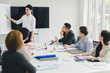 © Nawarit - A group of Asian businessmen are discussing. Employees are presenting their work to the meeting.