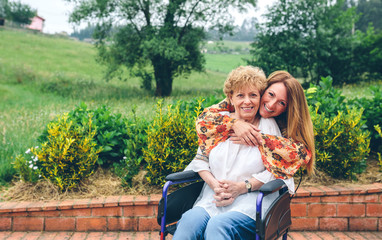 Daughter embracing her senior mother in wheelchair