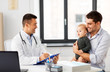 © Syda Productions - medicine, healthcare, pediatry and people concept - happy father with baby daughter and doctor with clipboard at medical office in hospital