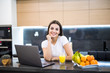 © F8  \ Suport Ukraine - Portrait of a young smiling woman sitting in front of her laptop in the kitchen