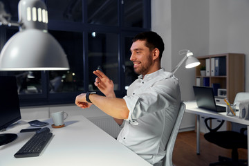 Wall Mural - business, technology and ai concept - smiling businessman using gestures with smartwatch at nigh off