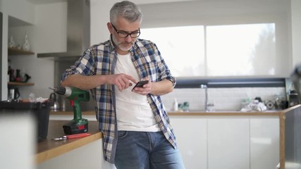 Wall Mural - Handyman checking cellphone in modern kitchen