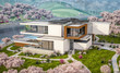 © korisbo - 3d rendering of modern cozy house by the river with garage. Fresh spring day with a blooming garden. For sale or rent with flowers of sakura on background.