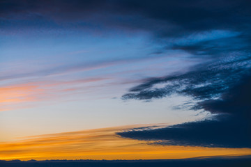 Amazing dramatic blue cloudy sky with orange sunshine in clouds. Atmospheric background in overcast weather. Storm warning. Beautiful dark cloudscape. Sunset. Sunrise. Dawn. Copy space.