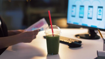 Wall Mural - business, technology and people concept - ui designer with smartphone templates on computer screen working on user interface design and drinking smoothie at dark night office