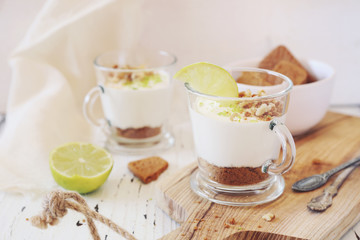 Lime cheesecake in two cups on light background