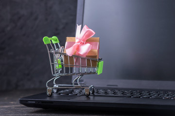 Daily purchases in the shopping cart on the laptop keyboard on a dark background. Shopping in online stores