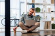 © LIGHTFIELD STUDIOS - handsome businessman sitting with crossed legs on floor and looking at laptop