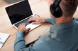 © LIGHTFIELD STUDIOS - selective focus of man listening music in headphones while using laptop with blank screen