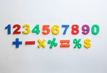Colorful magnetic numbers and math symbols on white background, top view