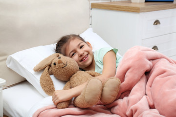 Wall Mural - Cute child with stuffed bunny resting in bed at hospital