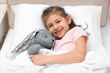 Wall Mural - Cute child with stuffed rabbit resting in bed at hospital