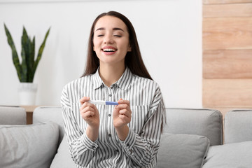 Poster - Young woman with pregnancy test at home. Gynecology and childbirth