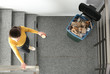 Young woman throwing coffee cup in trash bin indoors, top view. Waste recycling