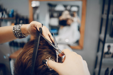 handsome young bearded guy sitting in an armchair in a beauty salon and the girl near him cuts his hair