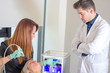 © GENETTICA - Doctor supervising the dermabrasion treatment that the beautician is going to apply to the patient in an aesthetic medicine clinic.