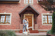 © Тарас Нагирняк - Young family bought a new home. Attractive men and woman with labrador near the big house. Couple looking at the camera.