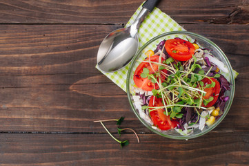 Wall Mural - Salad with red cabbage, radish sprouts, corn and tomatoes on wooden background with copy space