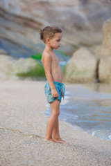 boy standing on the sand by the sea