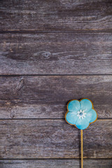 Sticker - Hand painted gingerbread blue flower on wooden background. Top view. Sweet dessert as a gift for women's day on 8 March