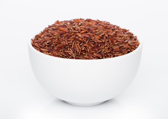 White bowl of raw organic red rice on white background. Healthy food.