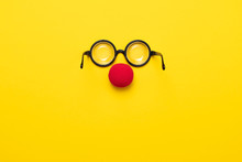 Funny Glasses, Red Clown Nose And Tie Lie On A Colored Background, Like A Face.