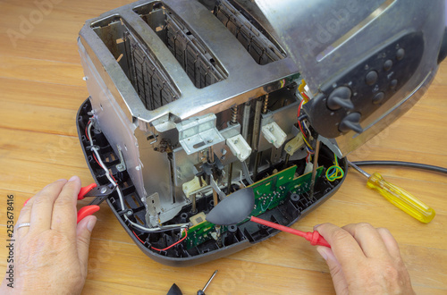 Concept Right to Repair, image showing hands of consumer repairing toaster with tools. Reduce waste by repairing household appliances.