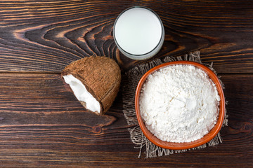 Coconut milk and flour on dark wooden background.