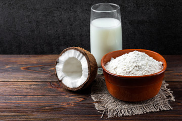 Coconut milk and flour on dark wooden background.