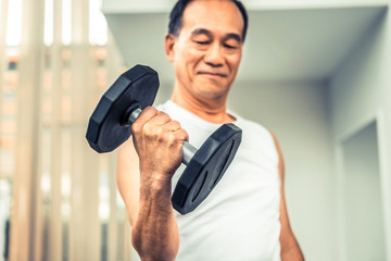 Wall Mural - Senior man lifting dumbbell in fitness gym. Senior healthy lifestyle.