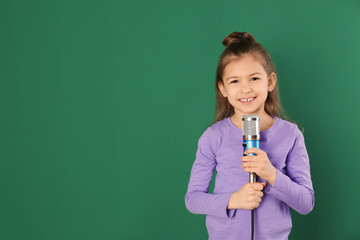 Canvas Print - Cute funny girl with microphone on color background. Space for text