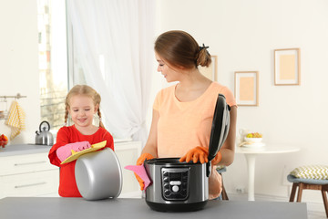 Canvas Print - Mother and daughter cleaning modern multi cooker in kitchen