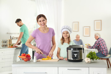 Canvas Print - Mother and daughter preparing food with modern multi cooker in kitchen