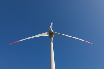 wind turbine with sun flare blue sky background view from below