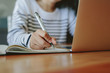 © Jacob Lund - Student taking notes with laptop on table