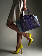 Beautiful Woman With A Slim Legs In Yellow High Heels. Fashionable Girl Holds Stylish Blue Bag.