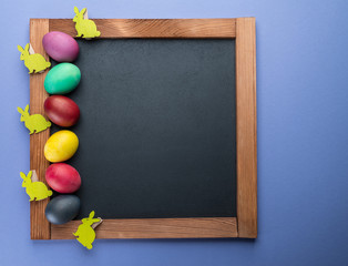 Wall Mural - Blackboard and colorful Easter eggs around it. View from above.