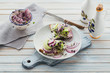 Healthy vegetarian bruschettas with bread, micro greens, cheese, cucumbers and red onion on light rustic wooden table