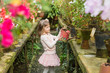 Little girl helps watering plants and gardening in greenhouse