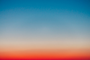 predawn clear sky with red horizon and blue atmosphere. smooth orange blue gradient of dawn sky. bac