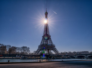 Wall Mural - The sun hiding behind the Eiffel tower