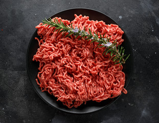 Fresh Raw mince, Minced beef, ground meat with herbs and spices on black plate