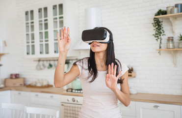 Wall Mural - Young woman in VR glasses in kitchen at home