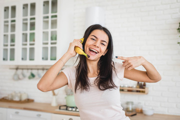 Wall Mural - Attractive woman is holding banana like a mobile phone, funny concept