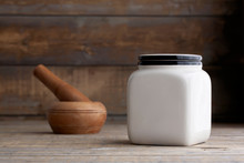 Mockup Of A Cream Ceramic Canister On A Wooden Table Next To A Pestle And Mortar.