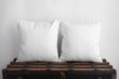 Mockup of two large white square cushions sitting on an old vintage suitcase
