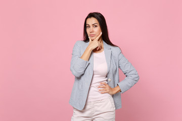 Portrait of confident young woman in striped jacket looking camera and put hand prop up on chin isolated on pink pastel wall background. People sincere emotions, lifestyle concept. Mock up copy space.