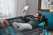 © Westend61 - Smiling man with tablet lying on couch at home