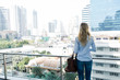 © Westend61 - Rear view of blond woman standing on balcony in the city