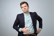 European young man in suit having stomach pain. Colic or flatulence